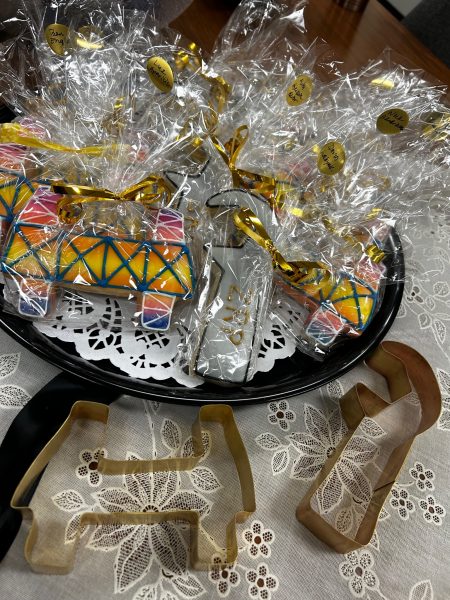 Bow of cellophane wrapped frosted cookies with cookie cutters on a table.