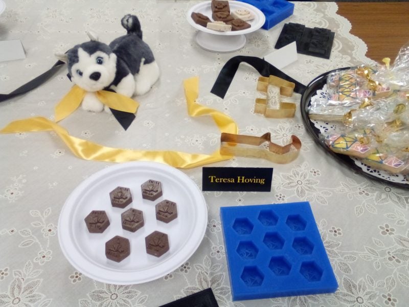 Five-sided chocolates on a plate plus a stuffed Husky dog toy and some cookies in cellophane and a blue silicon chocolate mold.