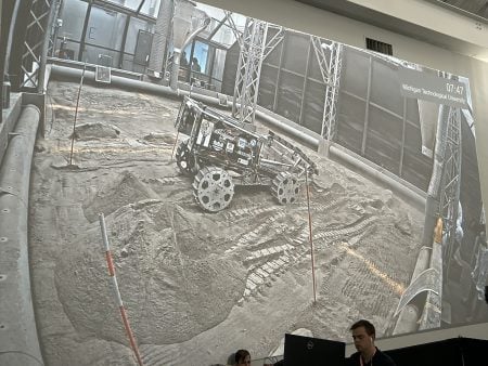 The ATLAS rover is projected onto a screen showing its capabilities maneuvering across a simulated lunar surface.