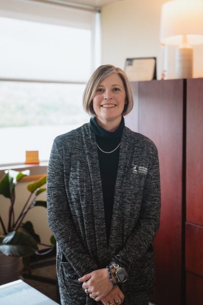 Audra Morse smiles in a portrait wearing a black turtleneck sweater and gray Michigan Tech cardigan.