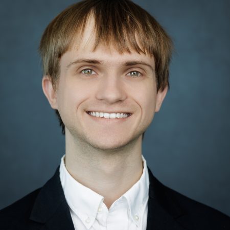 Geordan Gutow smiles in a professional headshot wearing a white shirt and black suit jacket.