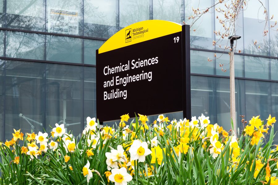Black Michigan Technological University sign that reads “Chemical Sciences and Engineering Building” surrounded by yellow daffodils in bloom.