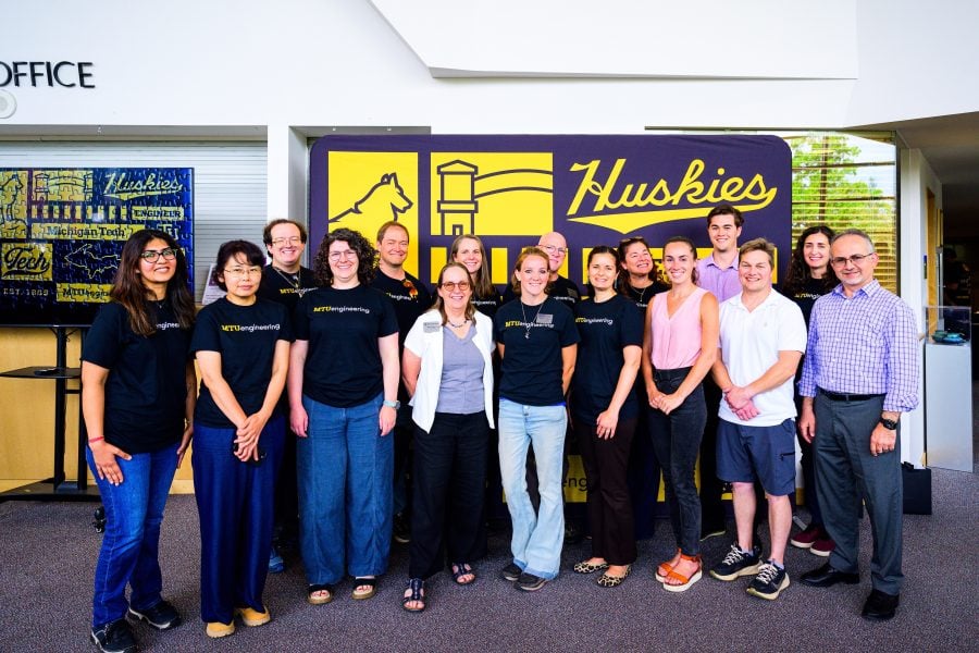 New faculty and staff from Michigan Tech’s College of Engineering pose with Dean Michelle Scherer in front of an MTU-branded photo backdrop.