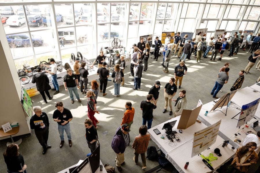 overhead view of the design expo with students standing near their presentation tables
