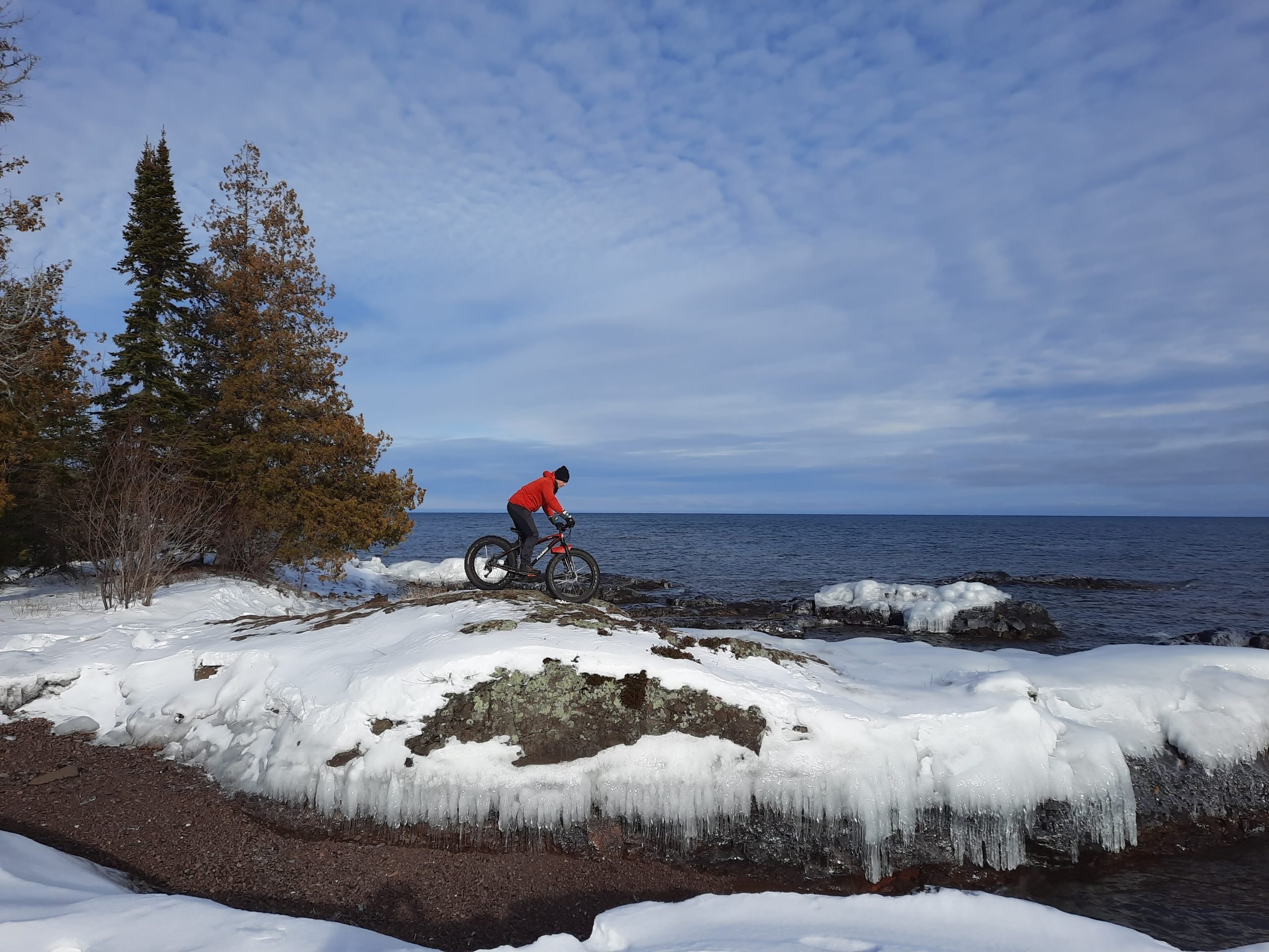 A person riding on a mountain bike on the lake coast.