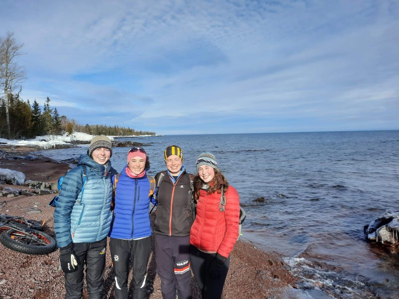 Four people posing in front of a beach coast