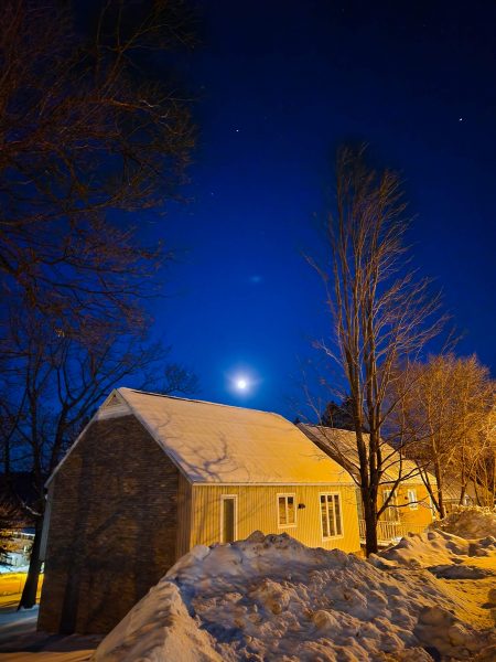 A residential building in the foreground, and the moon in the night sky in the background