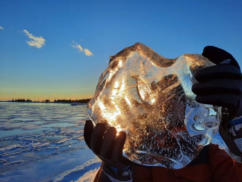 A man through a large chunk of ice at sunset