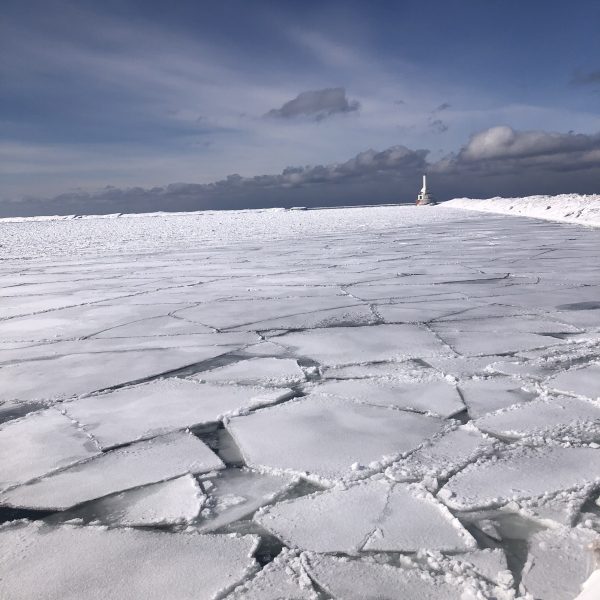 A frozen lake with a lighthouse in the distance