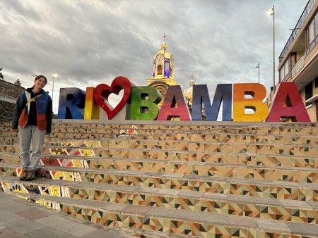 Quinn standing next to a colorful sign that reads Rio Bamba.