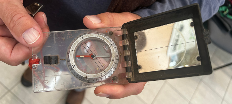 Hands holding a rectangular compass.