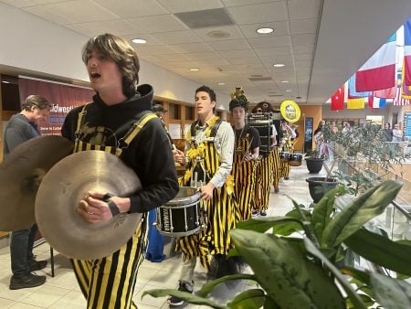 Pep band students walking through the upper level of the Forestry Atrium.