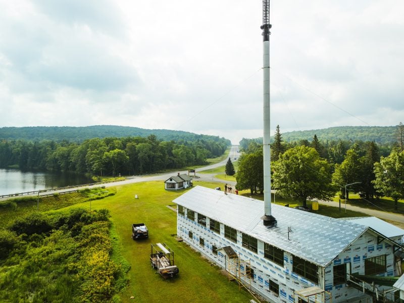 A low aerial view of the Ford Center Sawmill, showing the old siding stripped away and new installation in progress.