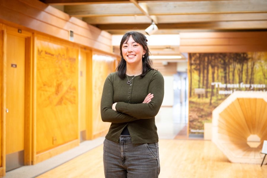 Quinn Riordan stands in the UJ Noblet Forestry Building, smiling with her arms crossed in a confident pose.