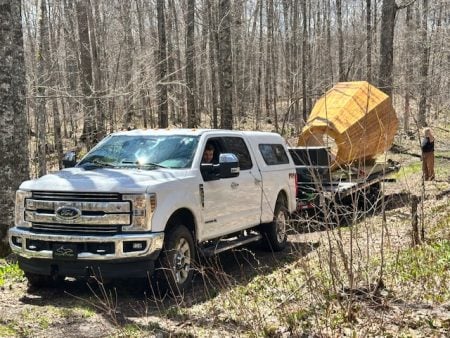 A truck hauls a trailer carrying a large wooden megaphone-shaped structure.