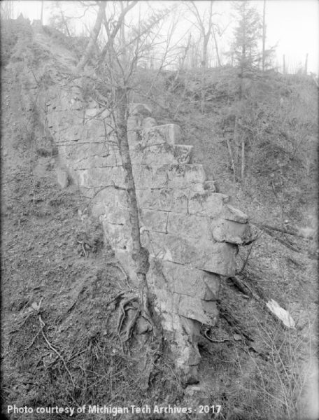 Historical photo of the Natural Wall geological feature on a hillside.