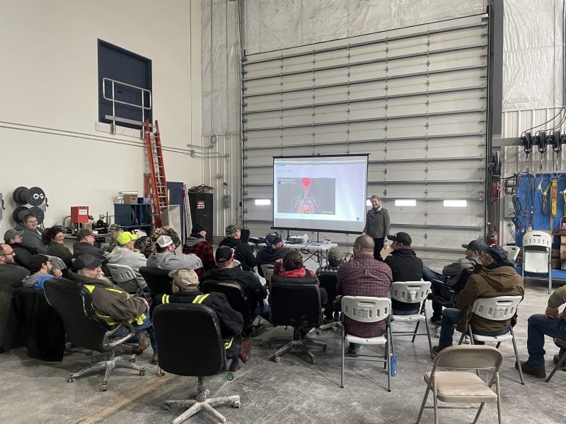 Mine Safety Trainer Marisa Roerig-Antuma conducts the class in an industrial garage setting using a screen and a slide show.