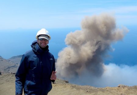 Simone standing at the BAciO 2016 workshop on Stromboli volcano, Italy, with a vibrant Strombolian volcanic eruption lighting up the sky in the background.
