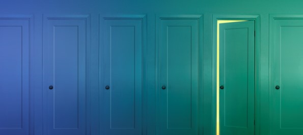 View of six doors, ranging in color from blue to green. The fifth half-open door symbolizes the possibilities of grad school.