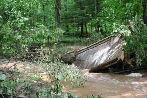 Broken bridge floating in Hancock's  trail system, which was destroyed by the Father's Day flood. This image demonstrates the damage caused by raging waters.