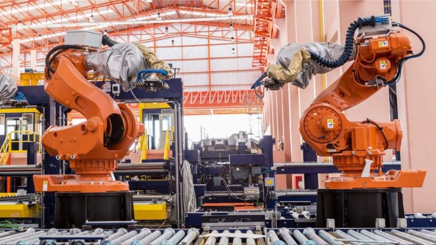 Two large orange robotic arms in a factory setting.