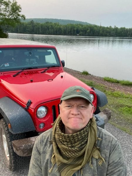 Jacque standing in front of his jeep during one of his adventures.