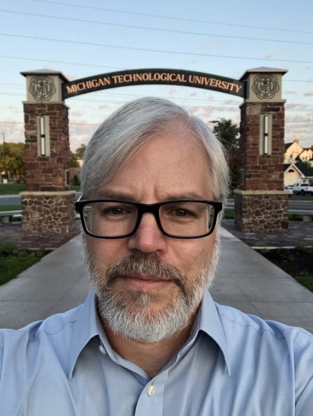 Rick Berkey stands in front of the Michigan Technological University arch.