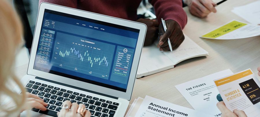 Investment bankers looking at a data visualization on a computer along with printouts of data. Investment banker is one of the data-driven careers for math majors. They use data to assess risks, make predictions, and analyze several factors.
