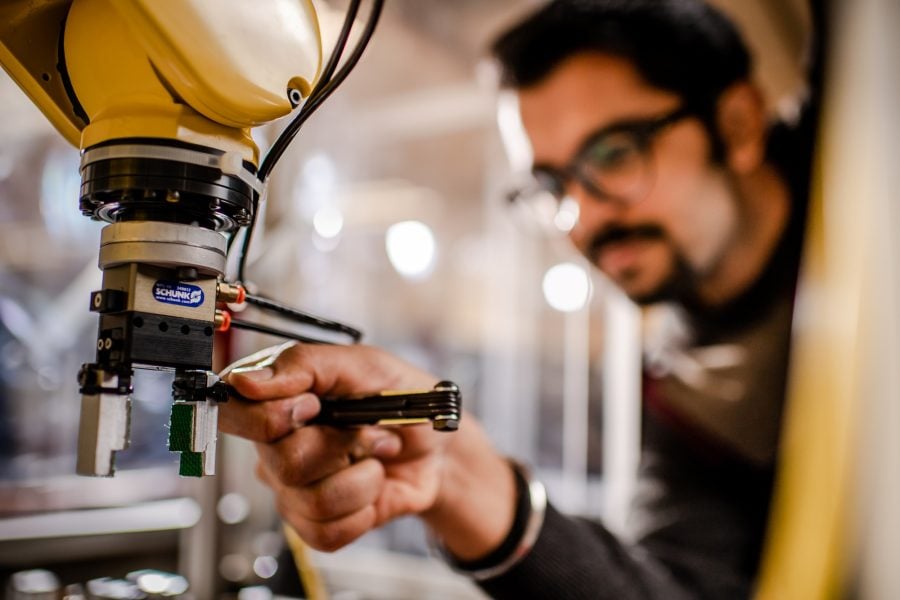 Manufacturing engineering professional working on a machine in a factory setting.