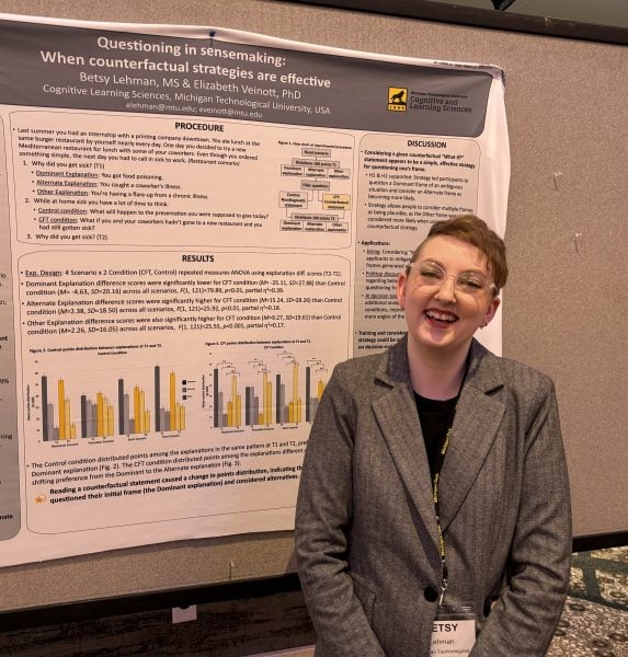 Elizabeth Lehman standing in front of a poster presentation at a conference
