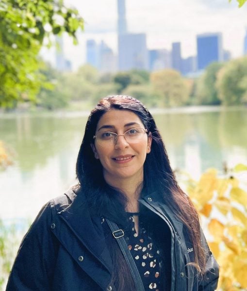 Fatemeh Razaviamri standing outside with body of water, trees, and cityscape behind