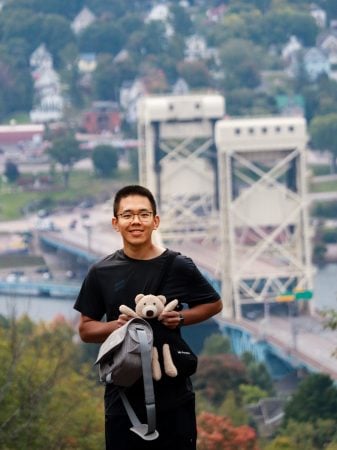 Peifeng Su standing outside with Portage Lake Lift Bridge in background