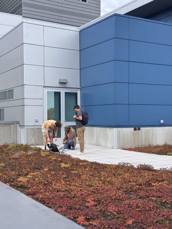 three people working on installing a project next to the GLRC green roof