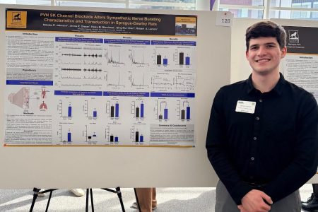 student standing next to research poster