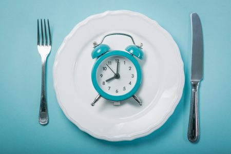 Intermittent fastin concept - empty plate on blue background,