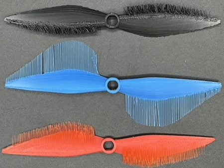 three 3D printed drone blades, with different hairlike textures on each edge.
