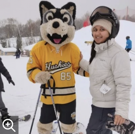 Sushree Dash and Husky mascot pose on the ski hill