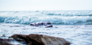 Waves in an ocean with rocks in the foreground.