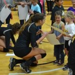 Stephanie Dietrich kneeling after a basketball game to young children