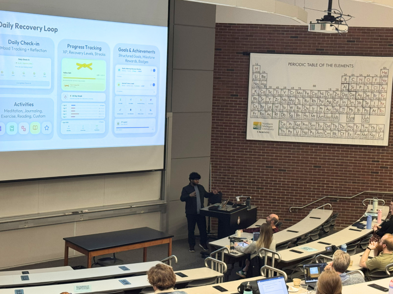 Nithish Raja Loganathan presents his project on a large projection screen to a group of students 
