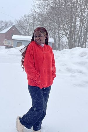 Milanzi stands on a street in the snow, smiling as she walks from house to house conducting a survey for her research project.