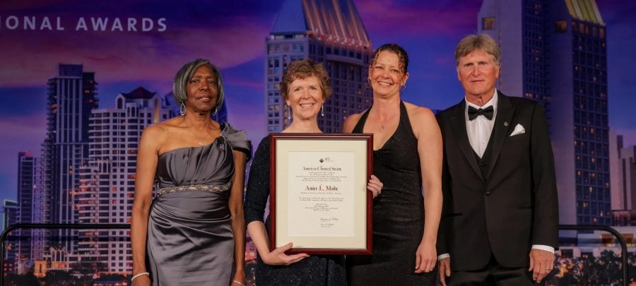 Aimee L. Modic poses at an awards ceremony with the 2025 James Bryant Conant Award in High School Chemistry Teaching, presented by the American Chemical Society. Three ceremony attendees stand next to her.