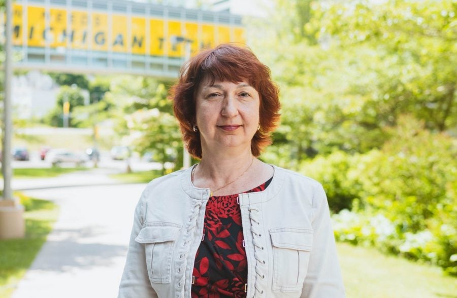 Rodica Curtu stands outdoors on a sunny day in front of the walking bridge between the Van Pelt and Opie Library and Rekhi Hall.