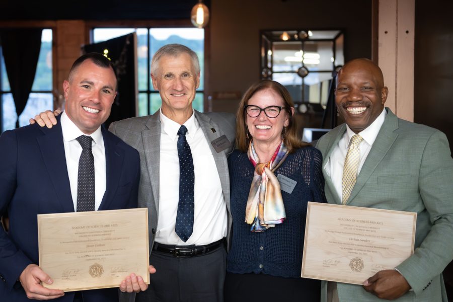 Steven Fantetti and Derhun Sanders, two new members of the Academy of Sciences and Arts, stand holding wooden plaques alongside University President Rick Koubek and CSA Dean LaReesa Wolfenbarger at the induction ceremony.