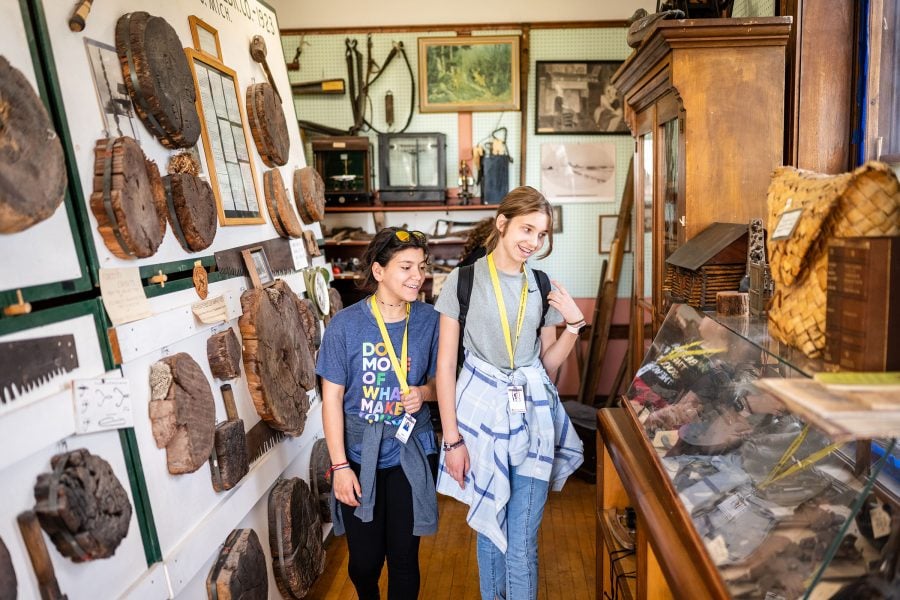 Two Summer Youth Program students view exhibits of mining and lumber history and tools with joyous curiosity at a local museum.