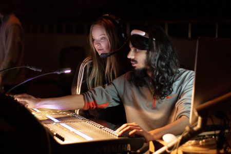 Satbit Mangat sits at an audio mixing board with a fellow Tech student.