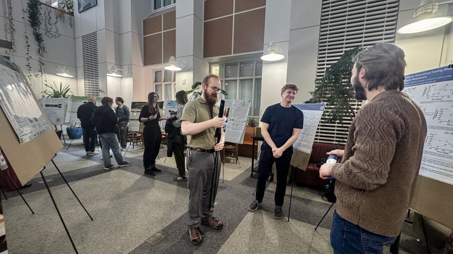 Elijah Nieman speaks with other students in a room filled with poster presentations at NMU.