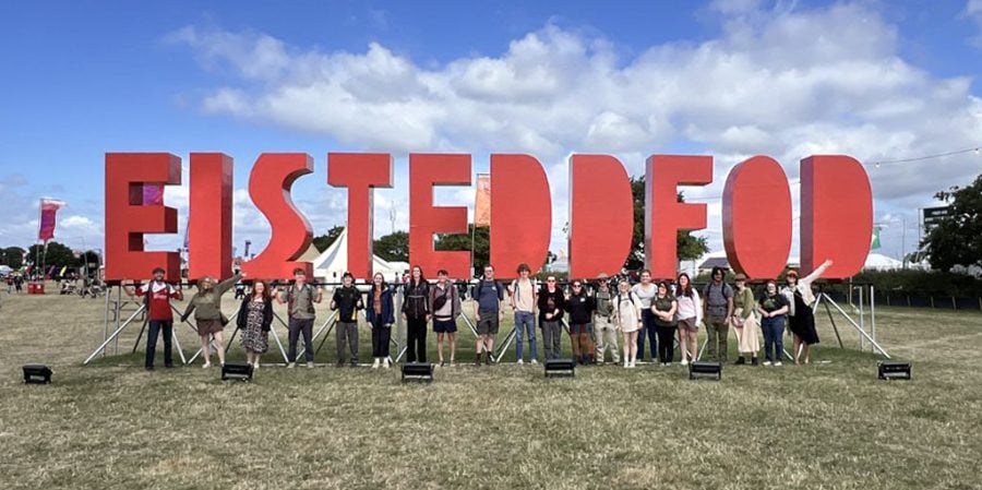 Michigan Tech students pose beneath a massive red sign that says, “Eisteddfod” during the festival in 2025.