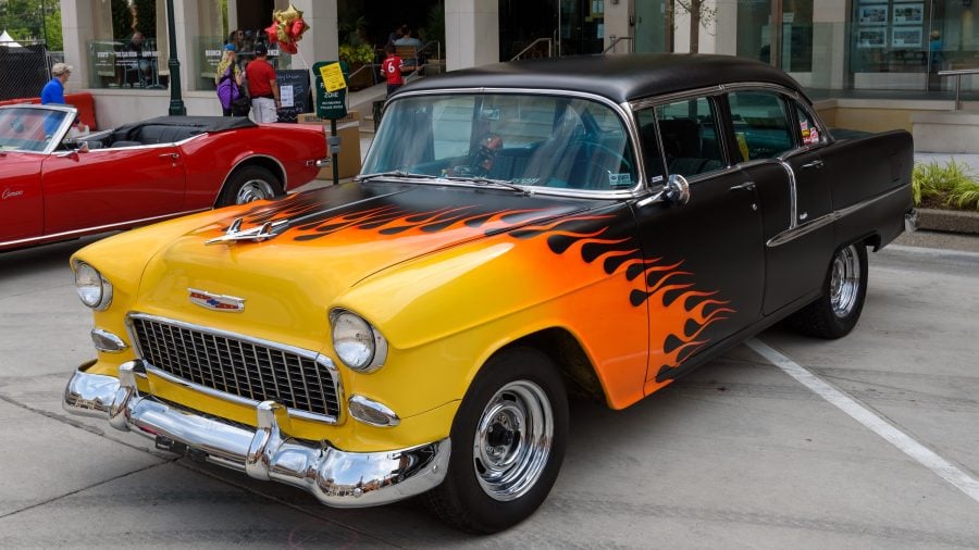 Black 1955 Chevy Sedan with yellow front fading into orange flames.