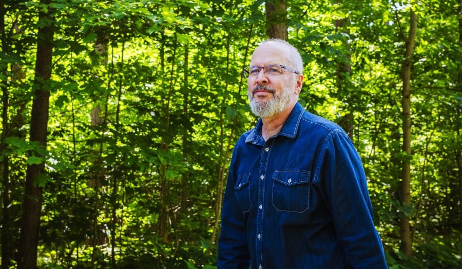 Michael Nelson in the woods looking into the distance.